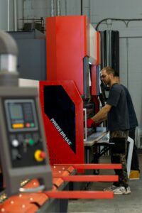 Technician operating a metal stamping press in a clean, bright manufacturing facility.