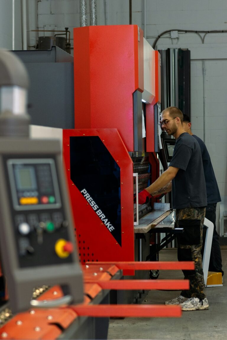 Technician operating a metal stamping press in a clean, bright manufacturing facility.