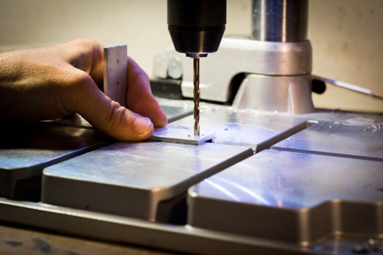 Technician inspecting metal components at a worktable inside a bright, organized manufacturing facility.
