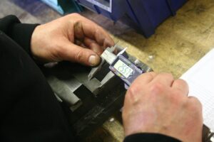 Technicians operate large stamping presses while forming metal components inside a well-lit industrial workshop.