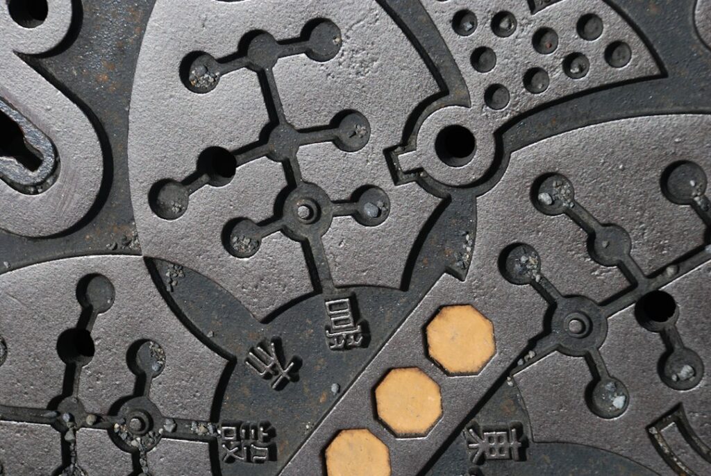 Engineer reviews a stamped metal part beside a drawing, calipers, and tooling samples on a workbench.